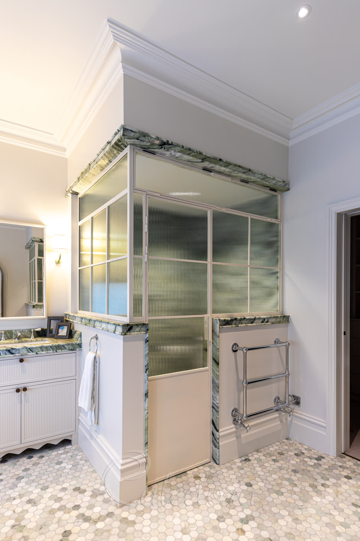 Glass shower enclosure with white powder-coated frame and central reeded glass section providing complete privacy