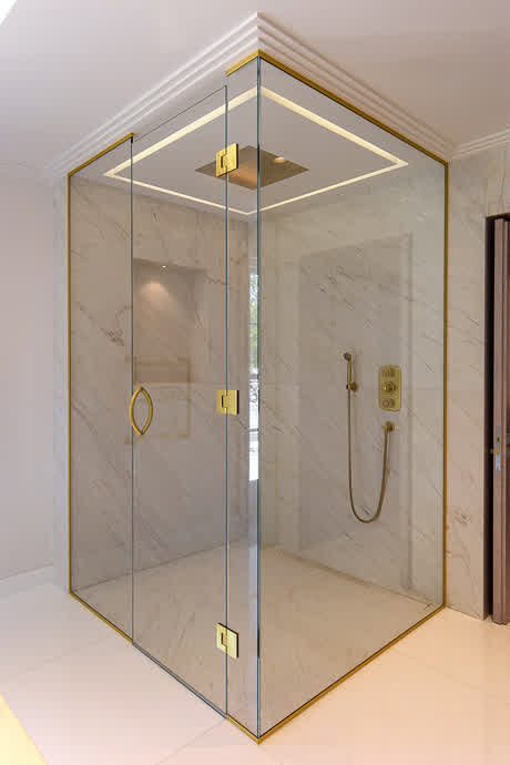 large shower enclosure to the ceiling with brass fixtures in a luxury interior
