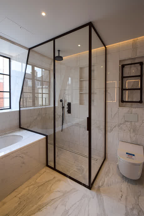 shower with bronze frame under sloped ceiling partially over a bath