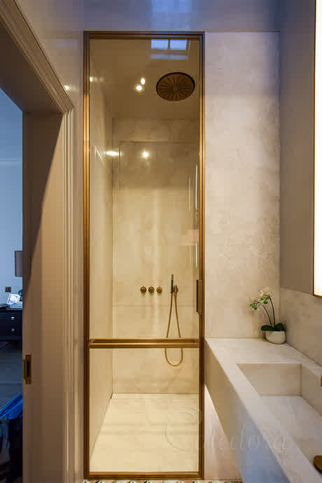 shower door with natural brass finish frame and a rail in the middle