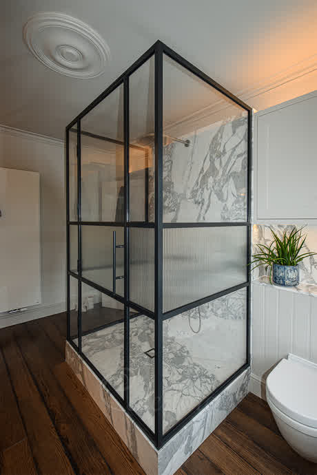 three sided shower enclosure with reeded glass in the middle and black premium frame around