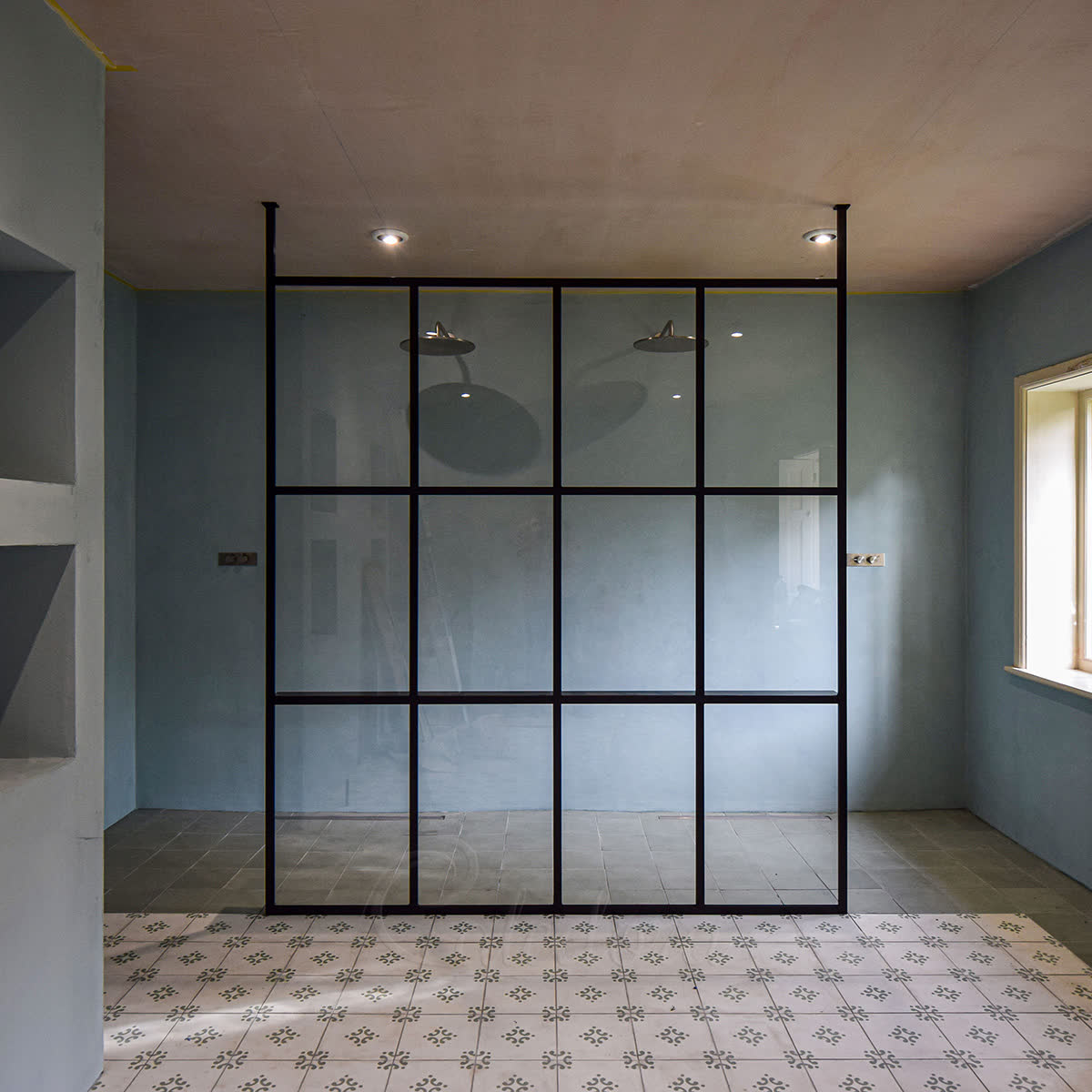 Walk-in shower glass screen with black-framed grid panel, two full-height structural posts, integrated shelf and double showerheads